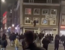A crowd of Israelis tear down a Palestinian flag hanging on a building in the city of Amsterdam. Hundreds of Israelis and fans of the notoriously racist Maccabi Tel Aviv soccer team had traveled to the city for a match in the city. Following a string of attacks and vandalism carried out by Israelis, the Maccabi fans were targeted in what the media dubbed an 'antisemitic pogrom'. (Screenshot, X)
